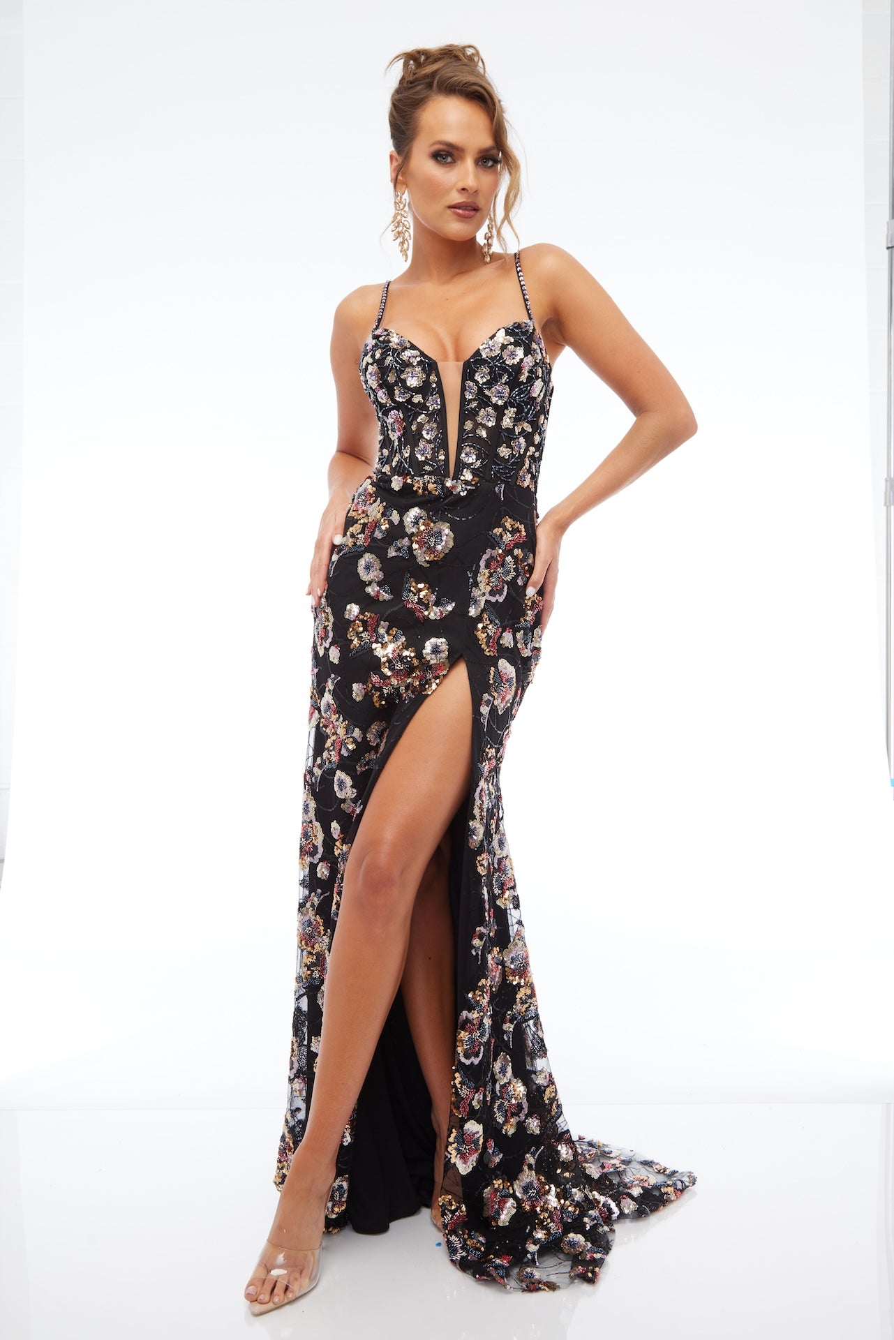 Front view of Style 7701: a multicolored prom dress featuring applique details, a high slit, a plunge neckline, and spaghetti straps.