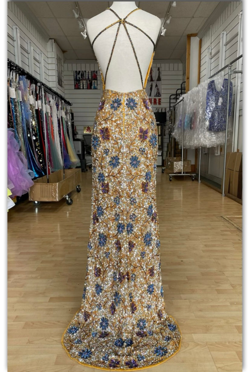 Back view of Style 7703: a dazzling beaded gold prom dress featuring a high slit, open back, and spaghetti straps.