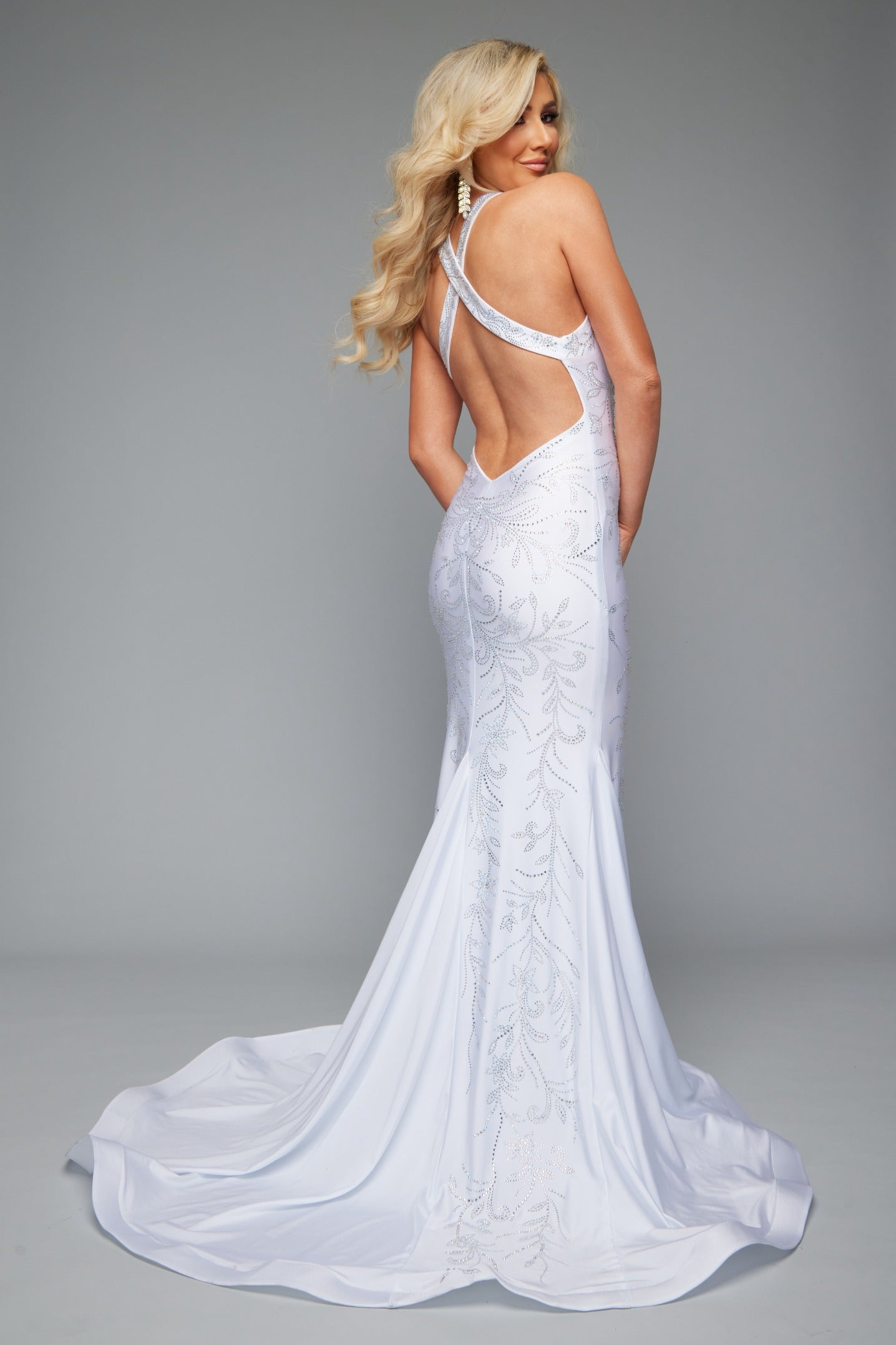 Back view of stunning white best selling fitted prom dress with a plunge neckline, open back, halter neckline, and applique design.