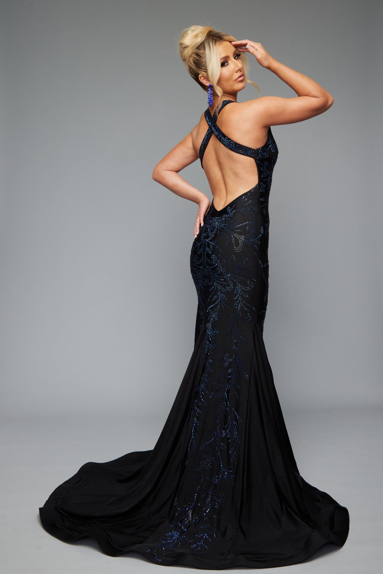 Back view of stunning black best selling fitted prom dress with a plunge neckline, open back, halter neckline, and applique design.