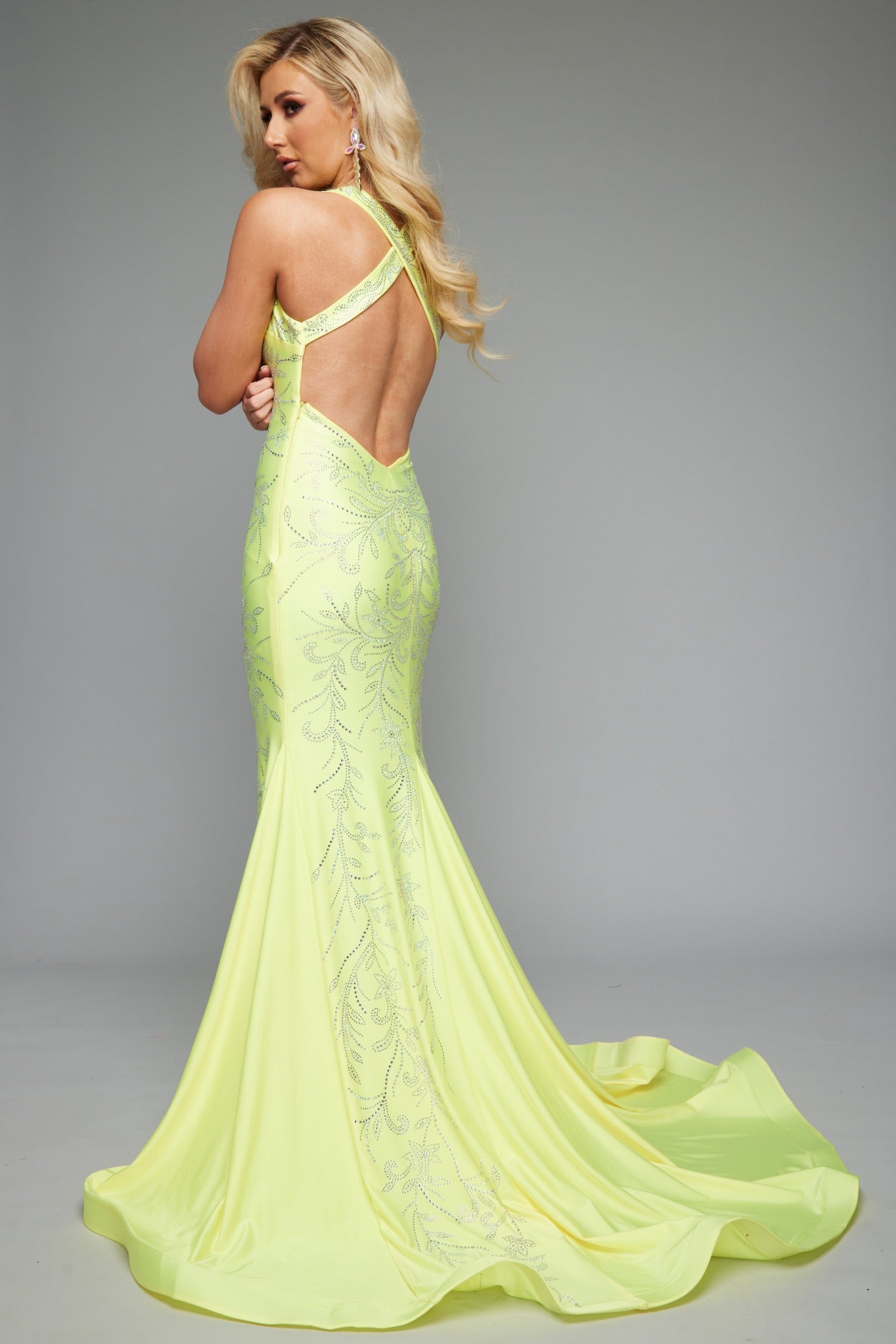 Back view of stunning yellow best selling fitted prom dress with a plunge neckline, open back, halter neckline, and applique design.