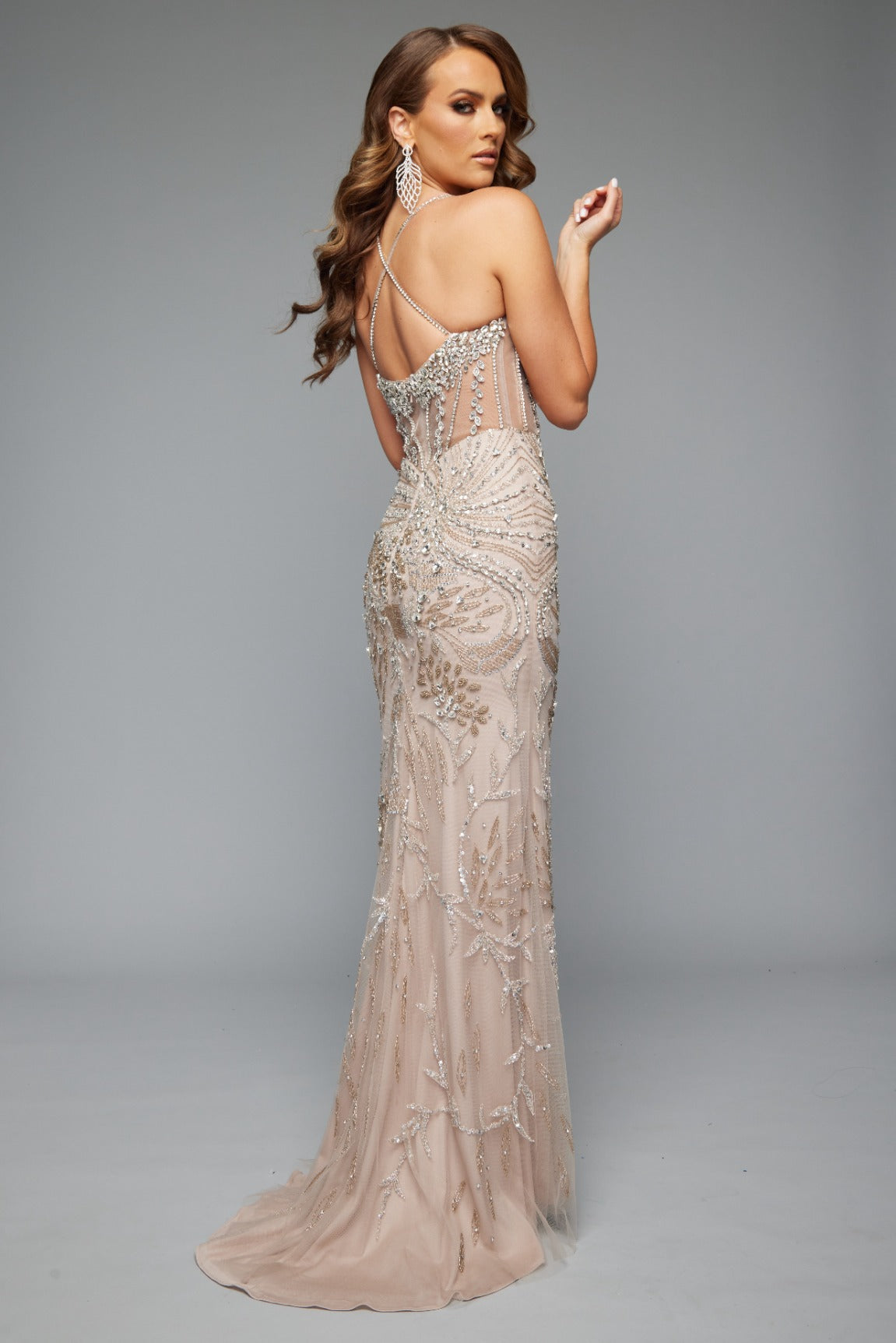 Back view of our glamorous fitted style 7610 in nude perfect for prom featuring a corset back, spaghetti straps, and a beaded applique design.