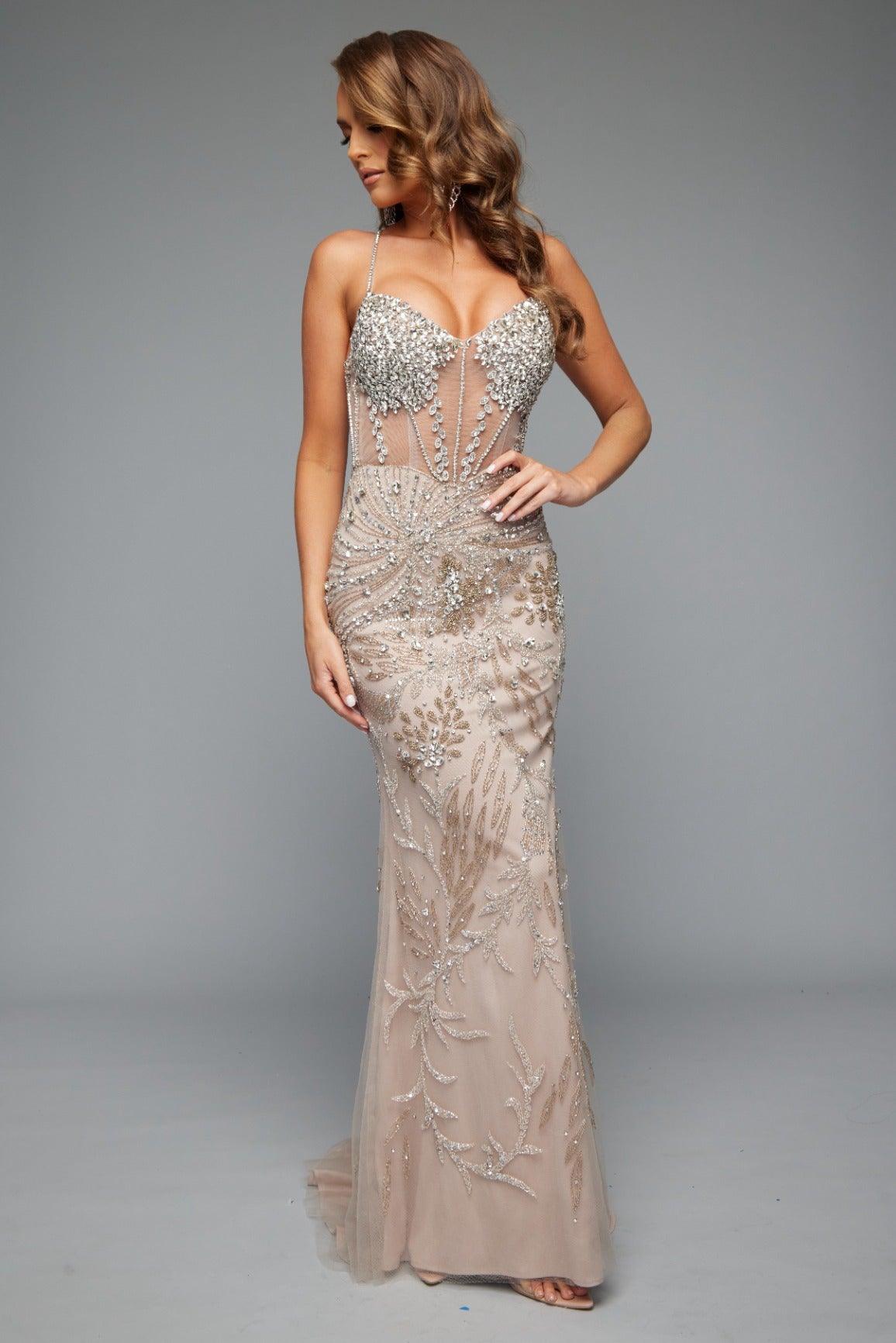 Front view of our glamorous fitted style 7610 in nude perfect for prom featuring a corset back, spaghetti straps, and a beaded applique design.