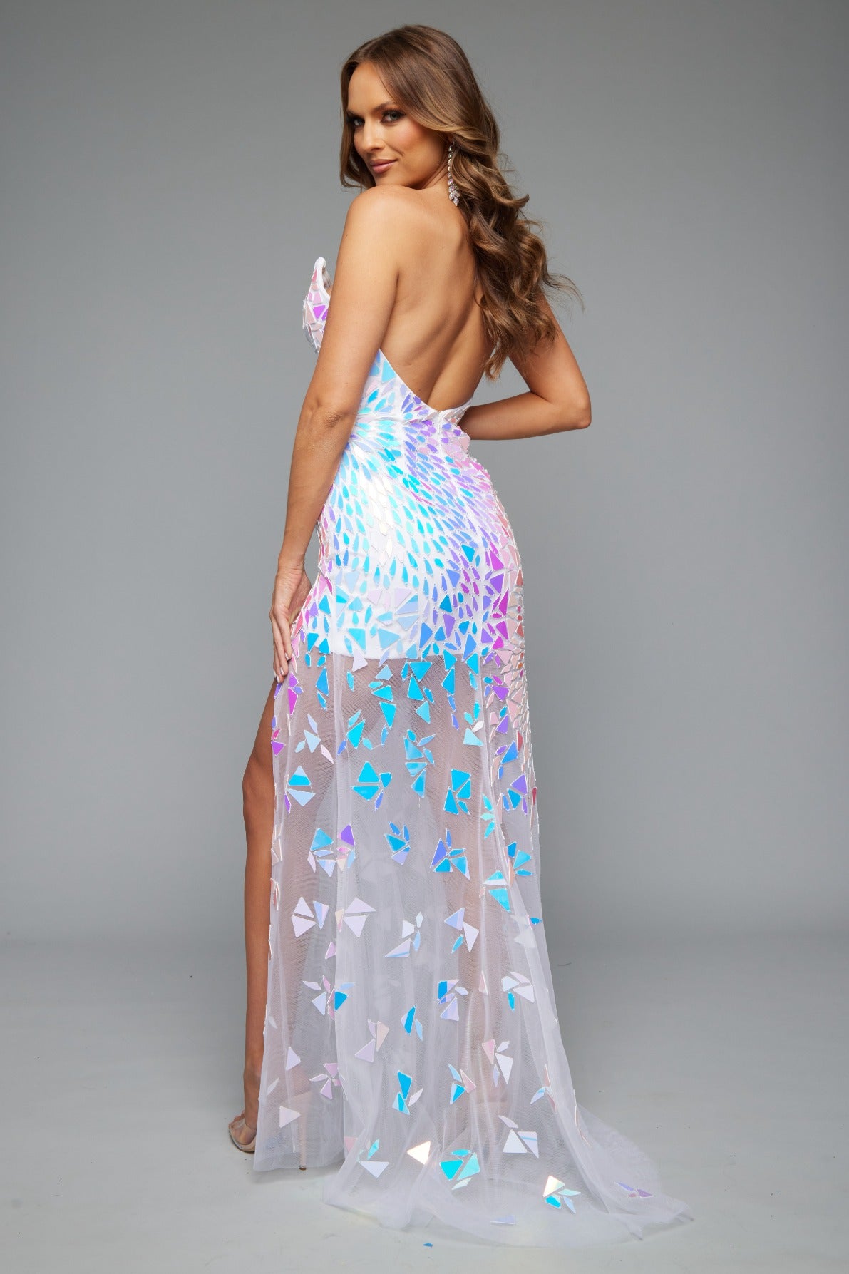 Back view of a dazzling white prom dress featuring a high slit, mirror accents, an open back, sheer skirt, and a strapless, sweetheart neckline.