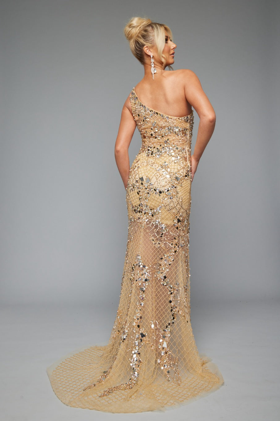 Back view of Jasz Couture Style 7653: an enchanting gold prom dress featuring a beaded netting design, high slit, and one shoulder.