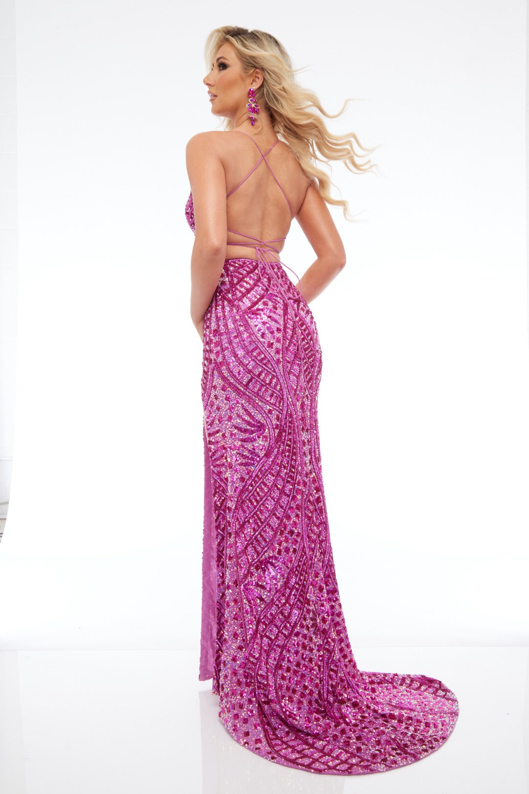 Back view of Jasz Couture Style 7672: a detailed fuchsia prom dress featuring a beaded design, high slit, lace up open back, and spaghetti straps.