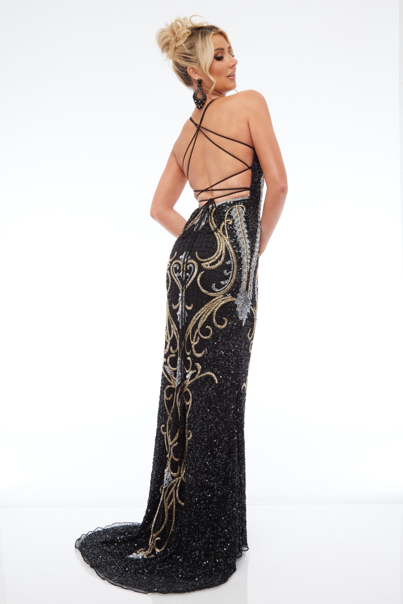 Back view of Style 7697: a beaded prom dress featuring applique details, halter, a high slit, and lace up back. Available in BLACK/GOLD/SILVER and ideal for turning heads.