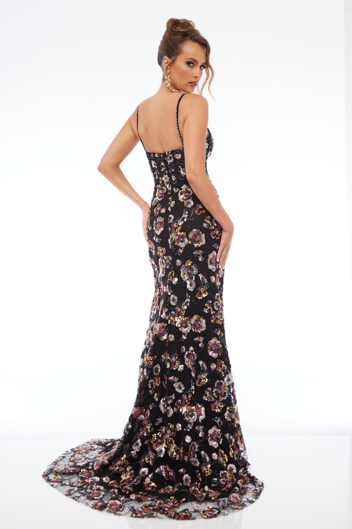 Back view of Style 7701: a multicolored prom dress featuring applique details, a high slit, a plunge neckline, and spaghetti straps.