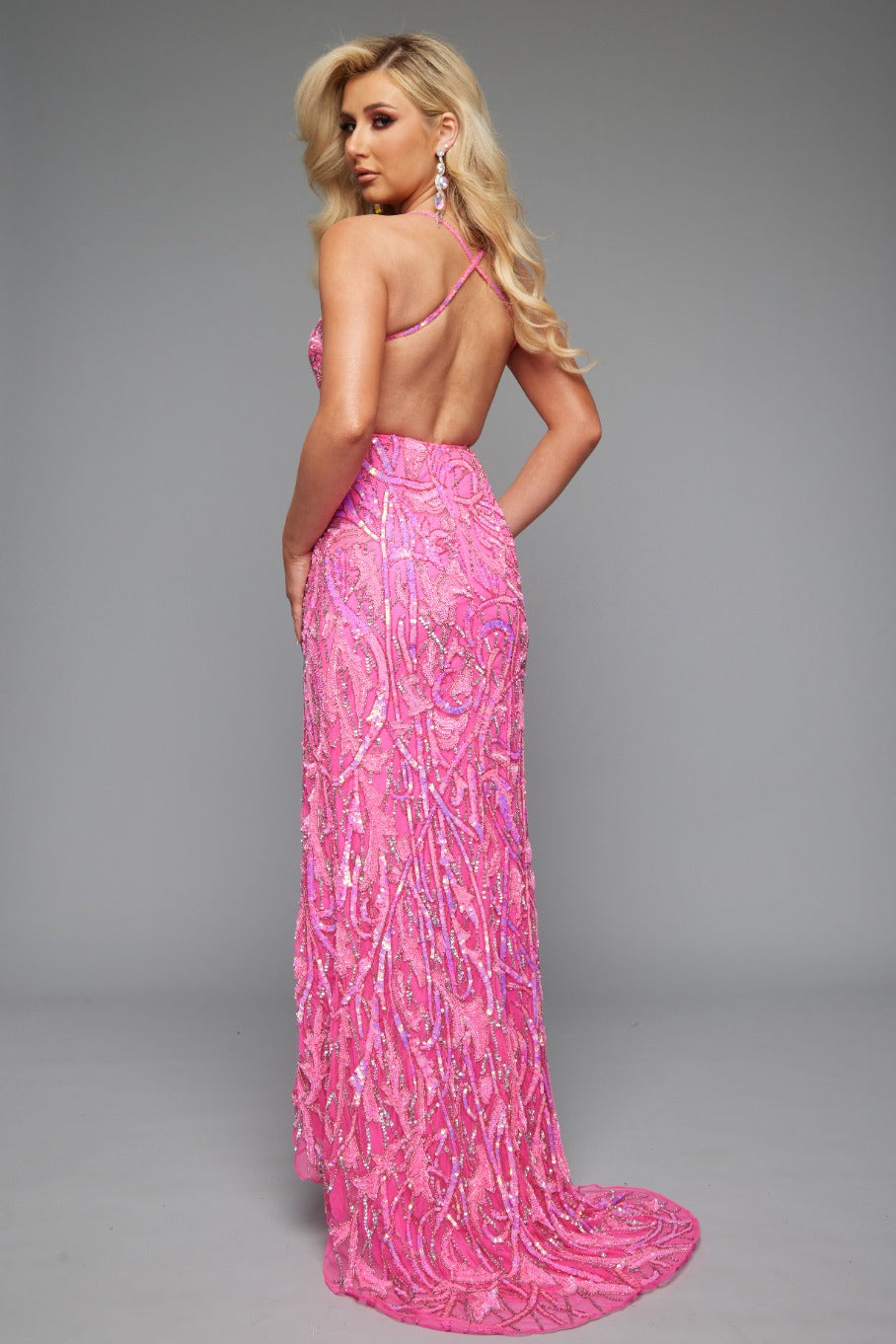 Back view of Style 7704: an elegant beaded hot pink prom dress featuring a high slit, open back, and spaghetti straps.