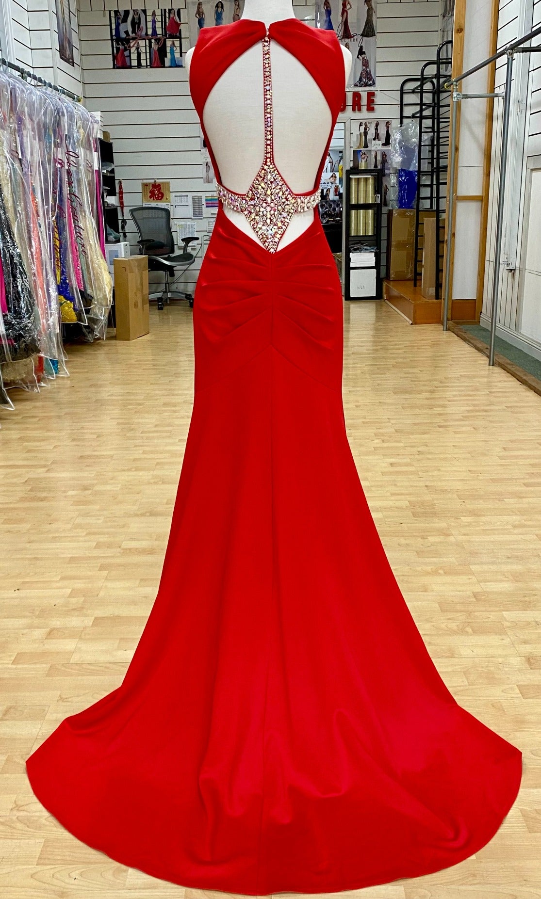 Back view of Style 7644: an elegant fitted red prom dress with beaded accents, an open back, and cutout plunge neckline.