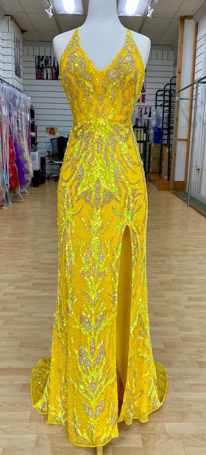 Front view of Style 7673: a captivating yellow prom dress featuring a detailed beaded design, halter, high slit, lace up back, and spaghetti straps.