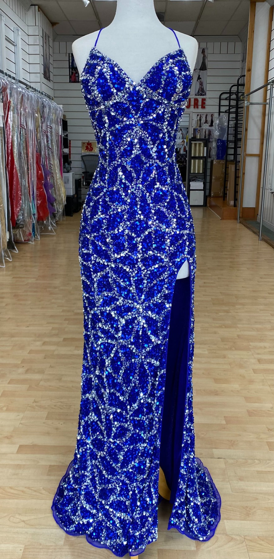 Front view of Style 7674: a dazzling beaded prom dress featuring a halter top, high slit, and a lace up open back. Shown in cobalt/silver.