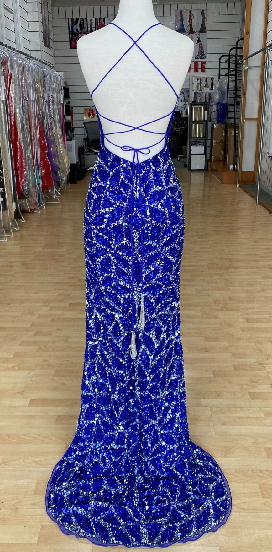 Back view of Style 7674: a dazzling beaded prom dress featuring a halter top, high slit, and a lace up open back. Shown in cobalt/silver.