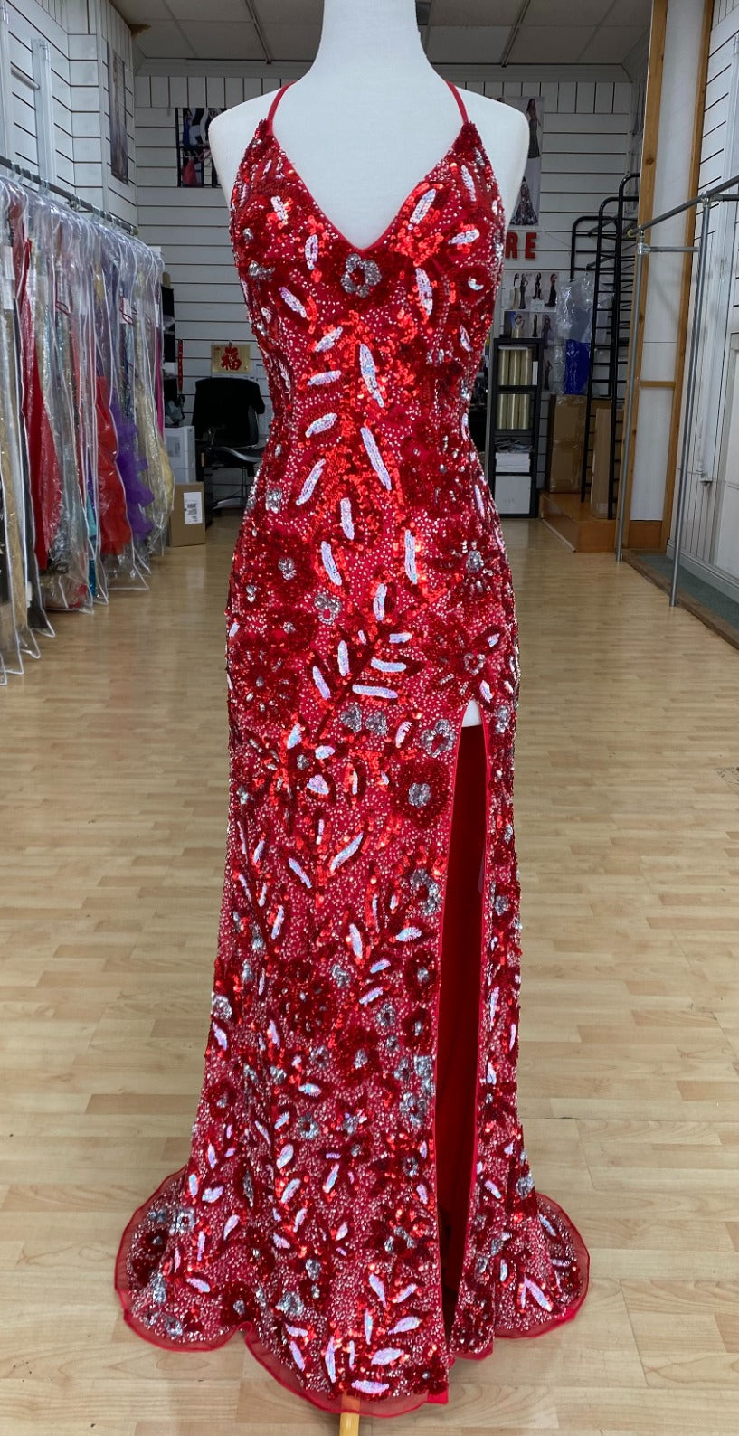 Front view of Style 7675: a dazzling fully beaded red prom dress with a halter, high slit, open back, and spaghetti straps.