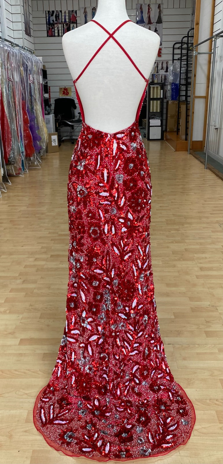 Back view of Style 7675: a dazzling fully beaded red prom dress with a halter, high slit, open back, and spaghetti straps.