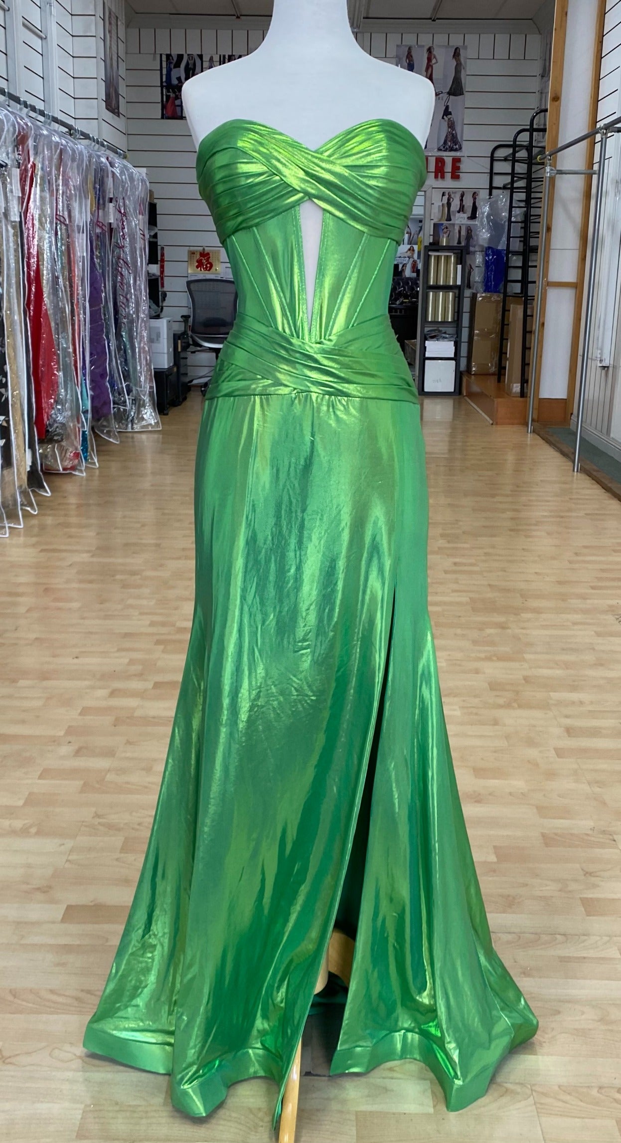 Front view of best selling Style 7705: a strapless prom dress featuring cutouts, a fitted design, a high slit, and a sweetheart neckline. Shown in green.