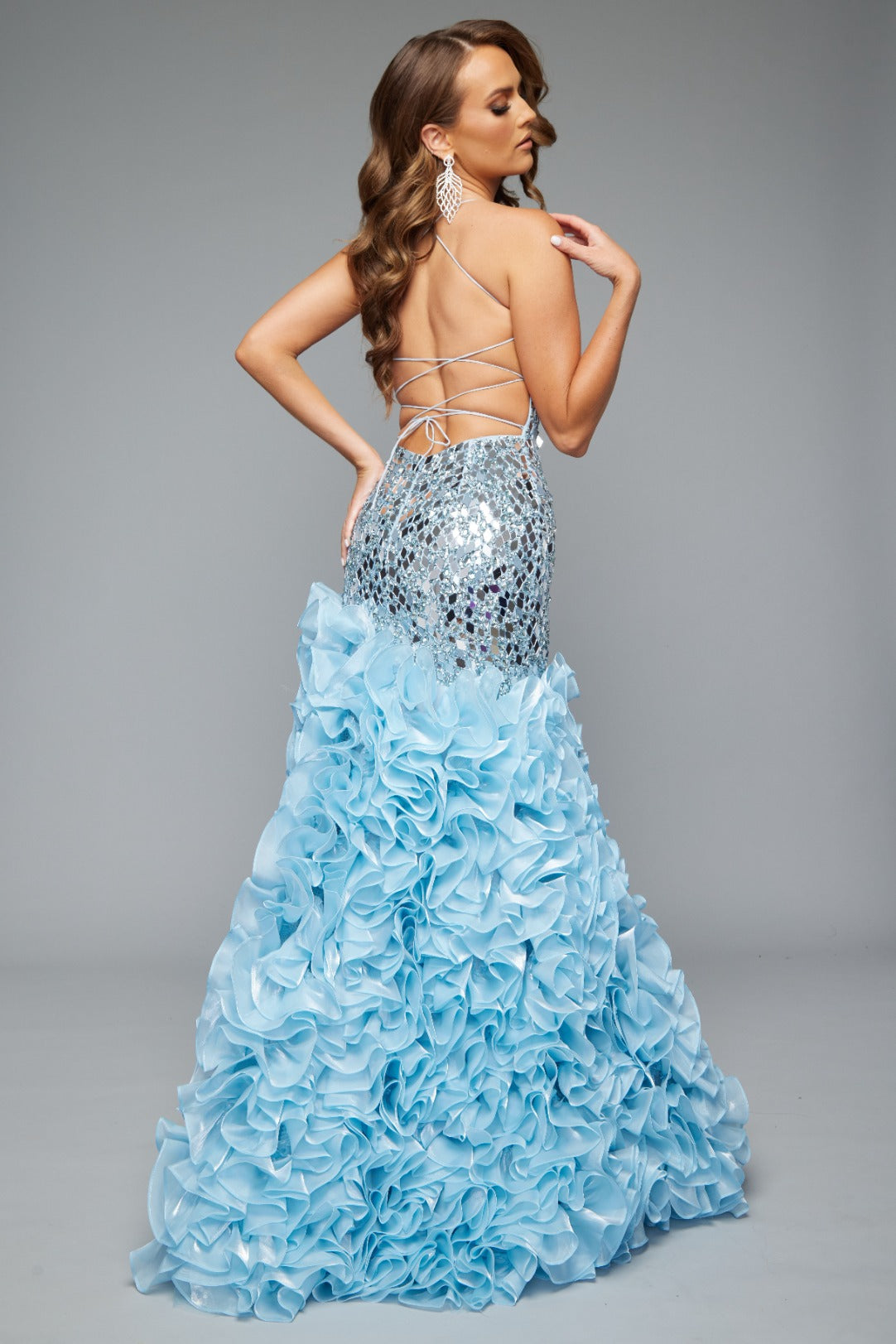 Back view of a radiant fitted sky blue prom dress with stunning mirror details, ruffle skirt, and lace up back design. 