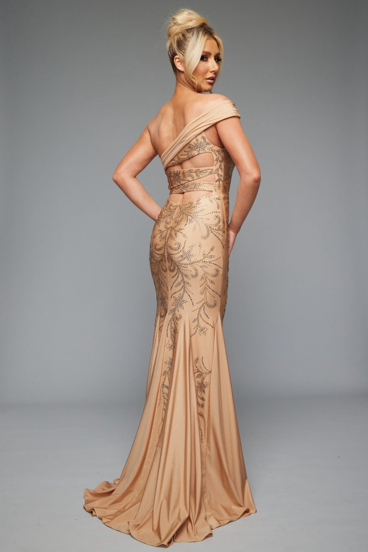 Back view of style 7621 prom dress with a beaded design, cut outs, and a unique one-shoulder off the shoulders neckline shown in NUDE, offering an elegant look.