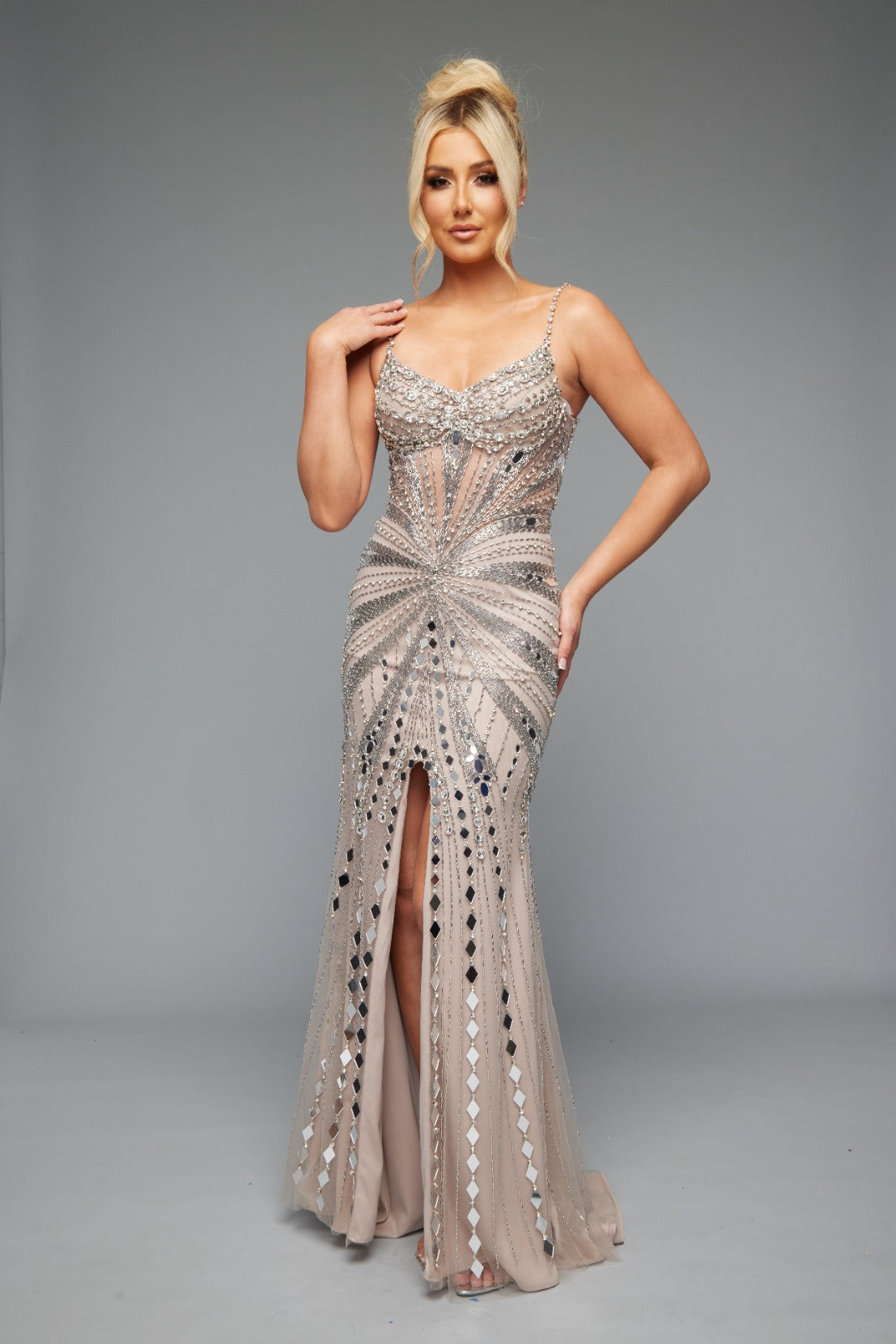 Front view of Style 7627: a refined prom dress featuring a beaded design, mirror accents, and spaghetti straps. Shown in nude and ideal for turning heads.